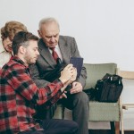 Zajęcia fotograficzne, fot. Kinga Liwak / Maciej Bielec | Na zdjęciu trójka osób, młody mężczyzna pokazuje coś na telefonie parze starszych osób.